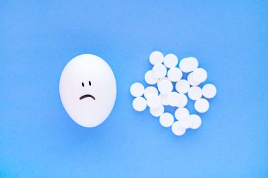 Yanlarındaki yumurtalarda gülen yüzler ve beyaz aspirin tabletleri. Sağlık ve mutluluk kavramı.