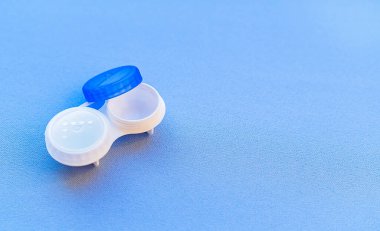 Kontak lens kutusu mavi arka planda açık. Yakın çekim ve yumuşak odak.