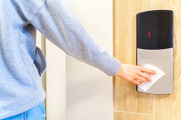 Людина натискає кнопку ліфта з туалетним папером під час епідемії коронавірусу та інфекційних захворювань. Профілактичні заходи для зменшення поширення вірусу грипу. Крупним планом і м'який фокус . Ліцензійні Стокові Фото
