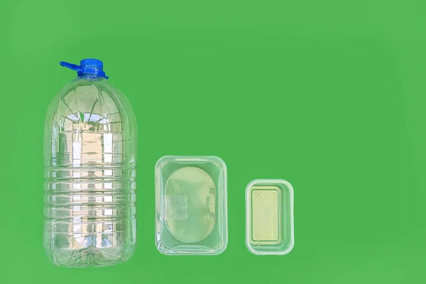 Recipientes de plástico e garrafa isolados em um fundo verde. Lixo de plástico — Fotografia de Stock