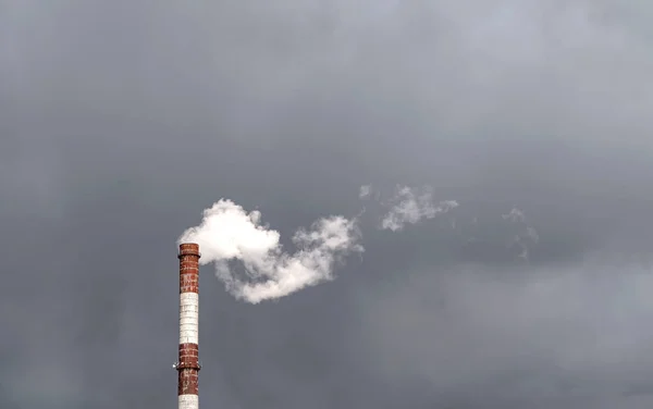 The chimney is isolated against a gloomy sky. Environmental pollution.