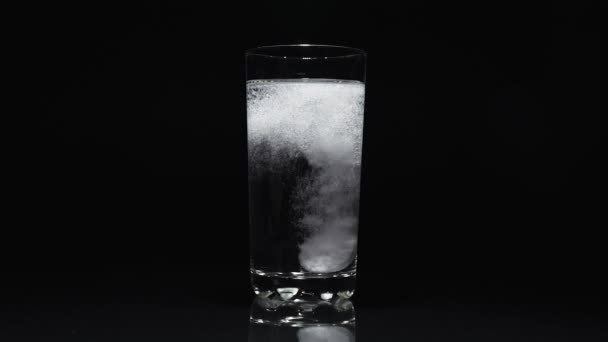 Un comprimé antiacide est dissous dans un verre d'eau sur fond noir .