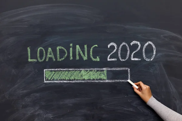 happy new year 2020. Chalkboard with 2020 loading text and loading percentage bar and hand