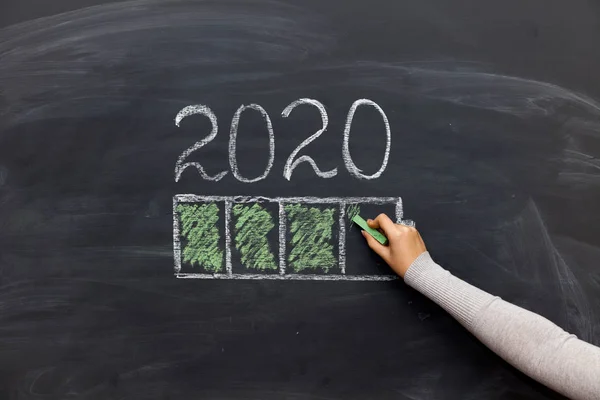 happy new year 2020. Chalkboard with 2020 loading text and loading percentage bar and hand