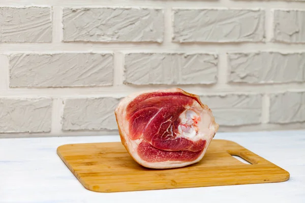 Raw pork knuckle. Cutting Board, background in the form of a brick wall