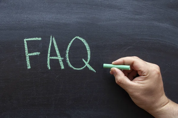 FAQ, frequently asked questions abbreviation, written on a blackboard in green chalk.