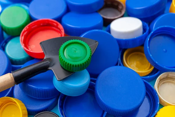 The concept of recycling plastic bottle caps. Plastic cover on a small shovel