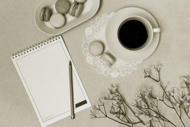 Boş not defteri, kahve ve mavi pastel masa üstü üzerinde renkli macaron görüntüleyin. Siyah ve beyaz, fotoğraf tonlama. Moda düz yatıyordu