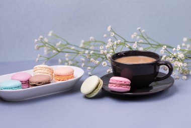 Yakın çekim sabah siyah süt, pasta macaron ve çiçek mavi masada kahve fincan. Güzel tatlı.