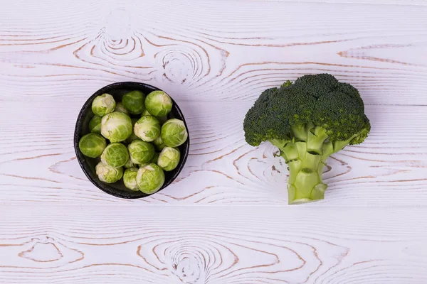 Brócolis frescos, brotos de Bruxelas em um boliche em uma mesa de madeira branca - produtos ecológicos, comida sã. Depósito plano — Fotografia de Stock