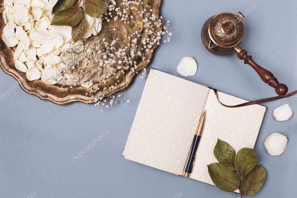 Autumn composition with petals of white roses on a vintage tray and an empty diary on a blue table, Coffee Turk . Flat layout, place for text.