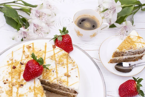 白盘上有奶油和坚果，草莓多汁，桌上有咖啡和鲜花的蛋糕. — 图库照片