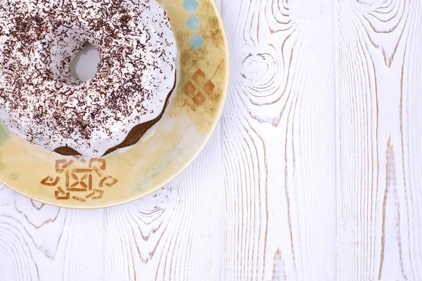 Bolo de Páscoa inglês tradicional caseiro coberto com cobertura branca e salsa de chocolate em uma placa de cerâmica em uma mesa de madeira branca em um estilo rústico. — Fotografia de Stock