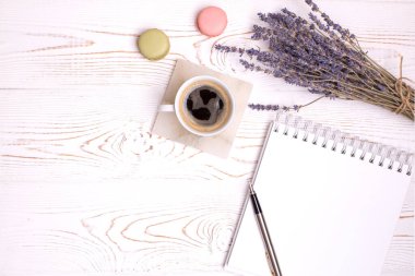 Boş günlükten, bir fincan kahveden, badem kurabiyesinden ve lavanta çiçeklerinden oluşan bir kompozisyon. Moda yatağı, kopyalama alanı.