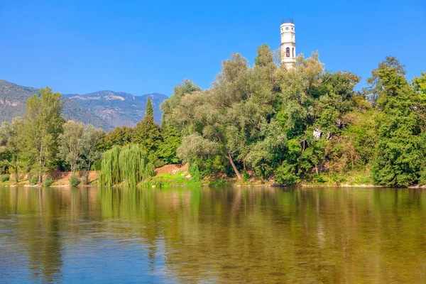 old white chapel on the river bank , scenery with flowing water