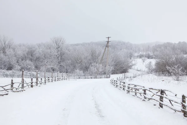 Tahta çitlerle çevrili karlı kış yolu