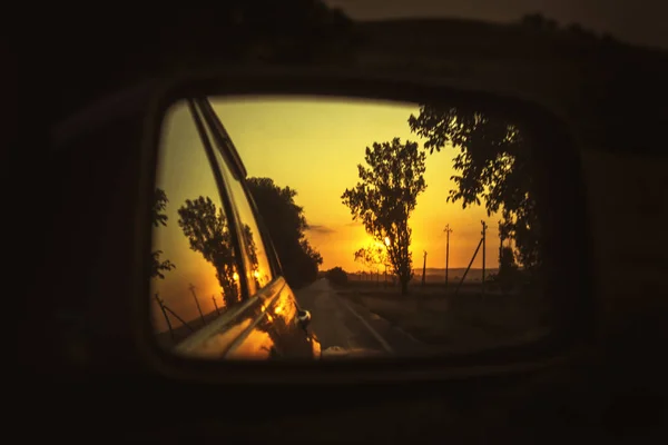 driving with sunset in the car mirror