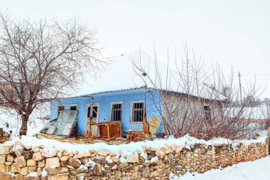 Terk edilmiş kır evi karla kaplı.