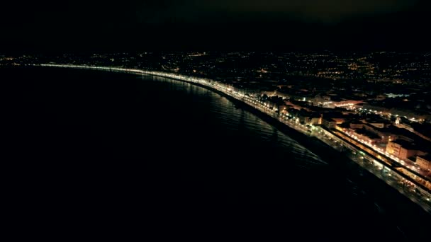 Vista aérea nocturna de la ciudad iluminada de Niza en Francia. Vuelo sobre el paseo marítimo y mar — Vídeo de stock