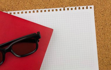 Boş kare beyaz kağıt sayfası metni Not Defteri'nden wrested. Orada gözlük siyah kalın jant, kırmızı defter ve mantar pano arka plan.