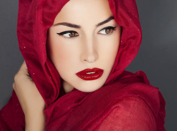 Beautiful woman portrait with red lips and red veil over her head, studio shot