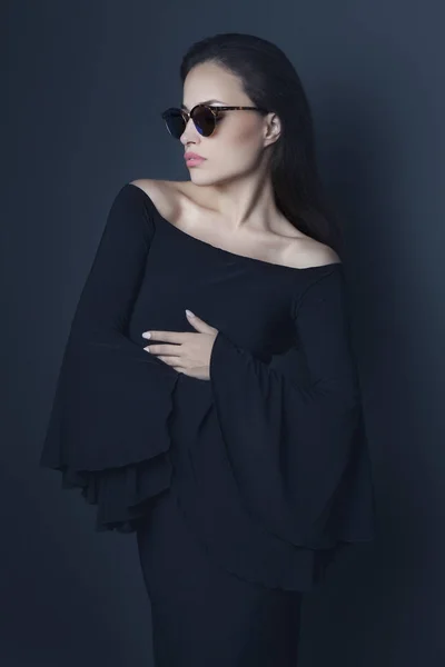Élégante jeune femme portant robe noire et lunettes de soleil — Photo