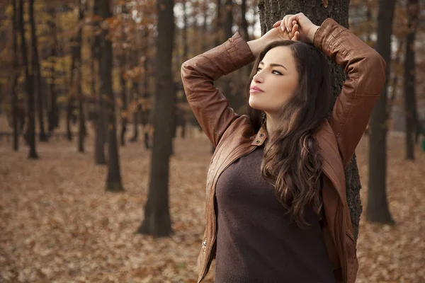 Jeune femme appuyée contre l'arbre regardant le ciel Image En Vente