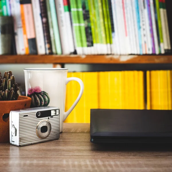 A minimalist  workplace with a cup of coffee and Laptop,cactus in the pot,old camera,minimal style