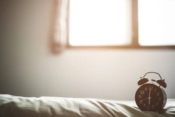 Conceptul de fundal dimineața, ceas deșteptător pe pat — Fotografie, imagine de stoc