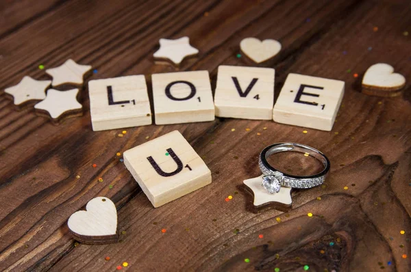 字母表字母木块瓷砖情人节的爱情概念与结婚戒指的木制背景 — 图库照片