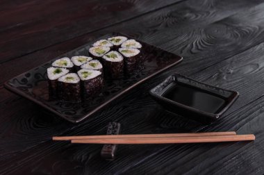 Rulo maki sushi siyah taş tabakta gelen çiçek. Taze yapılmış suşi peynir ve salatalık ile ayarlayın. Geleneksel Japon mutfağı. 