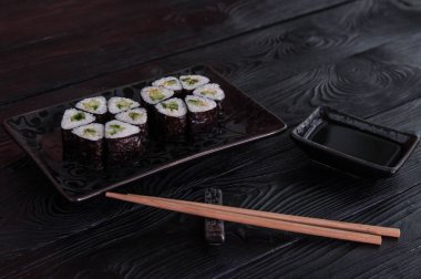 Rulo maki sushi siyah taş tabakta gelen çiçek. Taze yapılmış suşi peynir ve salatalık ile ayarlayın. Geleneksel Japon mutfağı. 