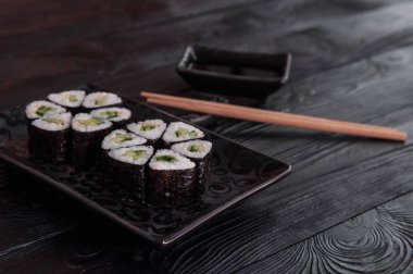 Rulo maki sushi siyah taş tabakta gelen çiçek. Taze yapılmış suşi peynir ve salatalık ile ayarlayın. Geleneksel Japon mutfağı. 