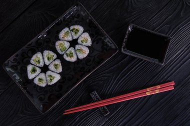 Rulo maki sushi siyah taş tabakta gelen çiçek. Taze yapılmış suşi peynir ve salatalık ile ayarlayın. Geleneksel Japon mutfağı. 