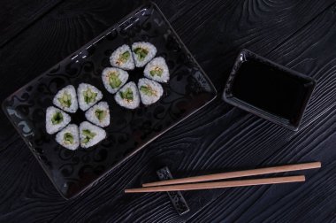 Rulo maki sushi siyah taş tabakta gelen çiçek. Taze yapılmış suşi peynir ve salatalık ile ayarlayın. Geleneksel Japon mutfağı. 