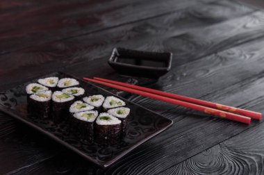 Rulo maki sushi siyah taş tabakta gelen çiçek. Taze yapılmış suşi peynir ve salatalık ile ayarlayın. Geleneksel Japon mutfağı. 