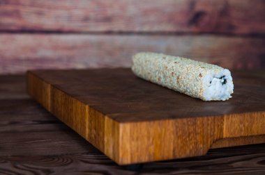 Maki sushi yapma işlemi. Peynir, salatalık ve susam rulo romaji maki sudare ile ahşap tahta üzerinde hazırlanıyor Şef eller yemek