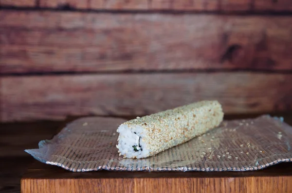 Process of making maki sushi. Cook chef hands preparing rolls with cheese, cucumber and sesame seeds on wooden board with romaji maki sudare