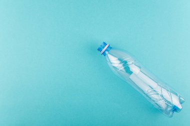 Mavi arka planda boş plastik şişe ve metin için kopyalama alanı. Plastik ve ekolojinin geri dönüşümü kavramı. Düz yatış, üst görünüm