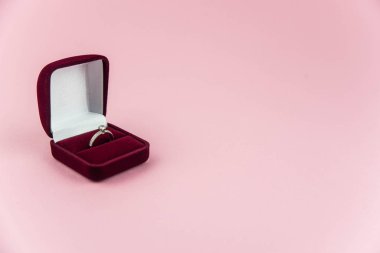 Pembe arka planda evlilik ya da nişan yüzüğü olan kırmızı kutu
