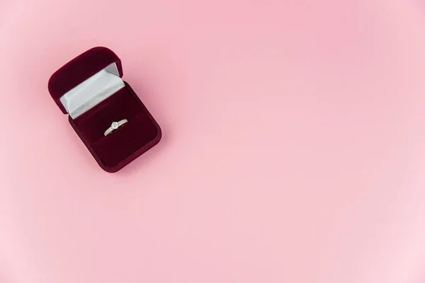 Pembe arka planda evlilik ya da nişan yüzüğü olan kırmızı kutu