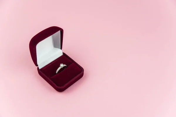 Pembe arka planda evlilik ya da nişan yüzüğü olan kırmızı kutu