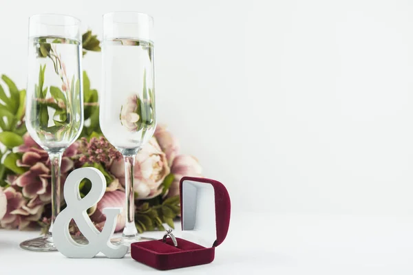 Marriage proposal and love concept for Valentine`s day, box with wedding or engagement ring with brilliant. Glass of champagne, romantic dinner, peony flowers on white background