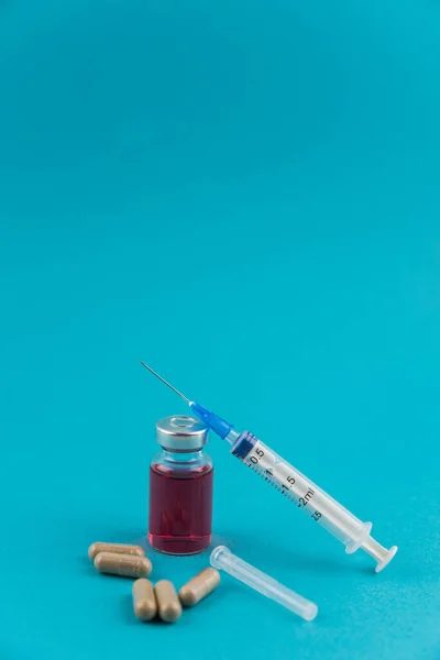 Medicine bottle for injection. Medical glass vials, syringe and drug pills for vaccination. Liquid red drug or vaccine for treatment, flu in laboratory, hospital, healthcare, or pharmacy concept, isolated.