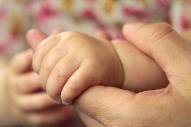 Bebek annesinin parmağını tutuyor.