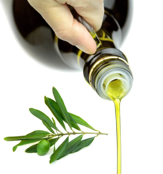 Pouring extra virgin olive oil from glass bottle with green olive branch. — Stock Photo, Image