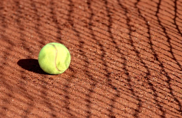 Bola de tênis em um campo de barro de tênis — Fotografia de Stock