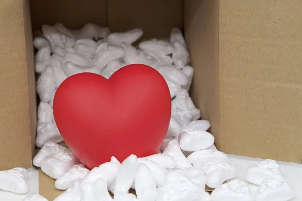 Red heart in mail package box with styrofoam