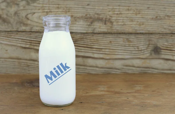 Milch und alte Flaschen auf Holztisch — Stockfoto