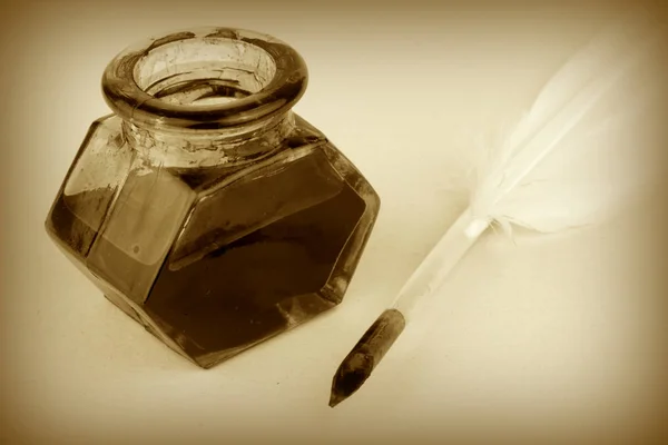 Quill pen and glass ink bottle on paper — Stock Photo, Image